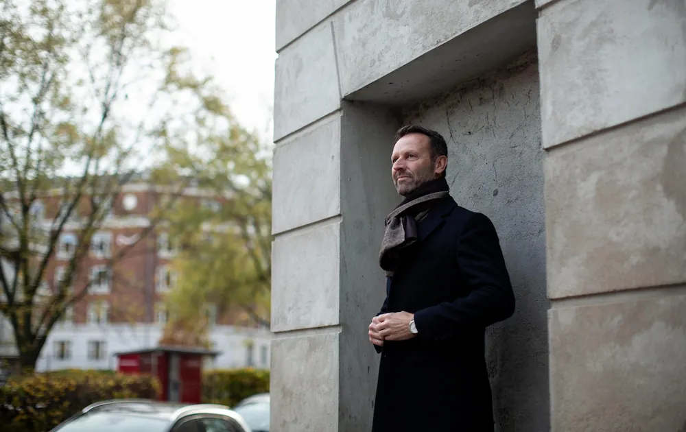 Q-Interline CEO Martin R. Henriksen press photo, scarf standing at wall